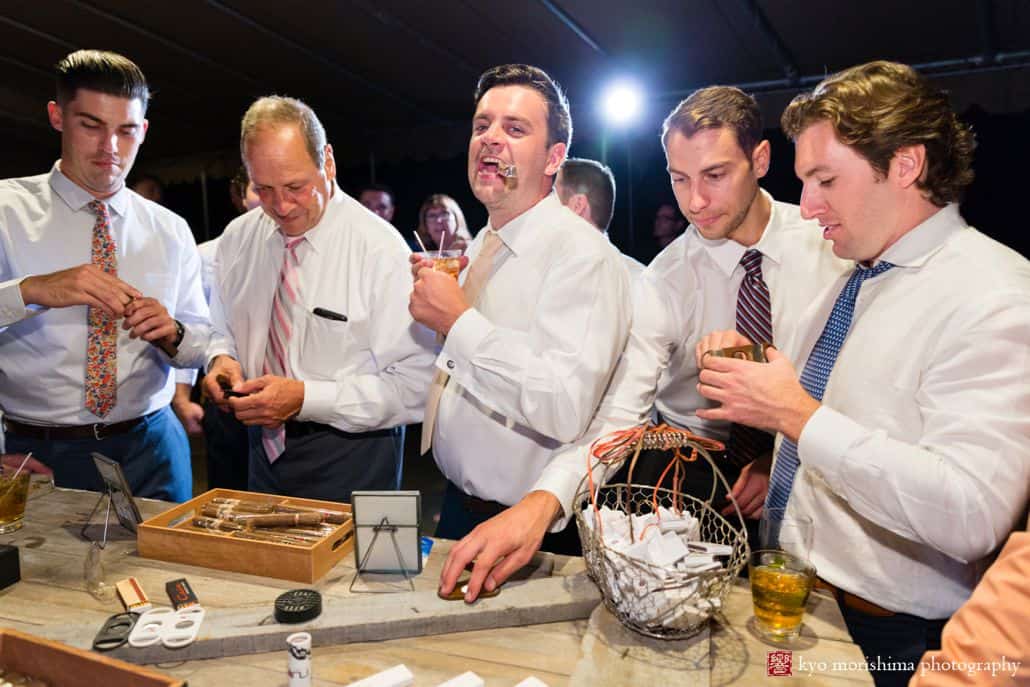 Groomsmen gather at table with cigars and drinks at Woodloch Pines resort, Poconos Summer wedding photographer.