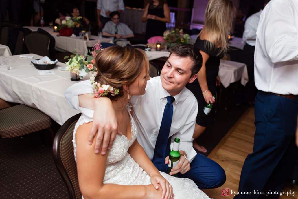 Bride and groom sit together and look at one another towards end of reception at Woodloch Pines in Poconos, Castle Couture bridal gown, Poconos wedding photographer.