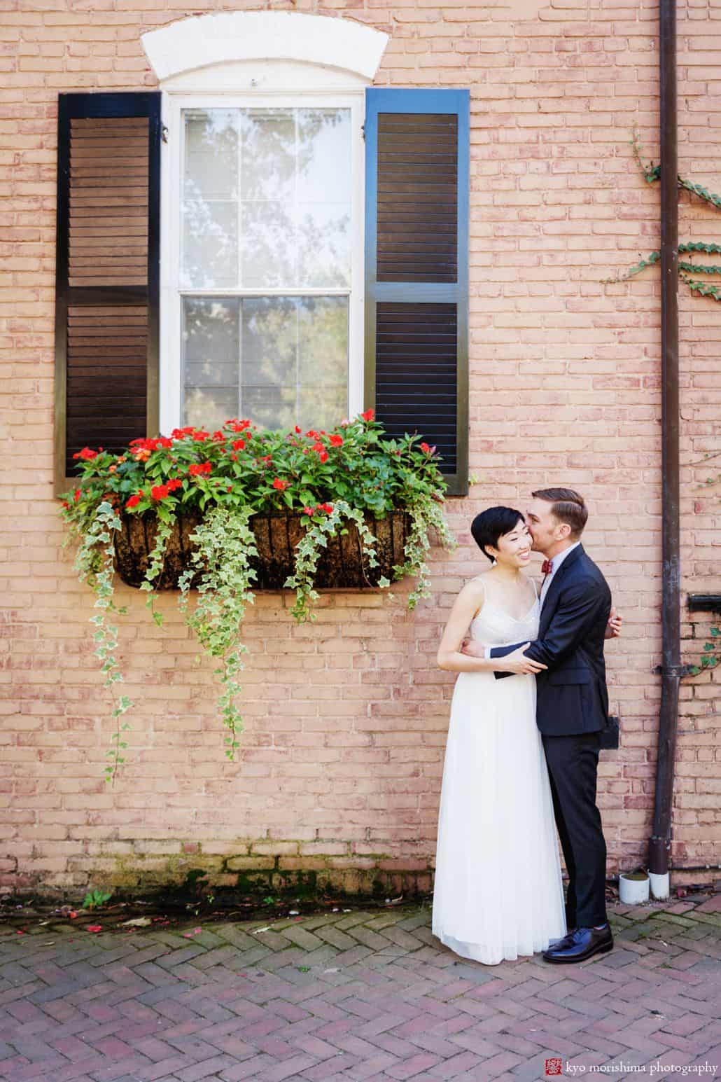 Bride and groom portrait against brick wall in Old Town Alexandria before their ceremony at small unique wedding venue Carlyle House in Old Town Alexandria