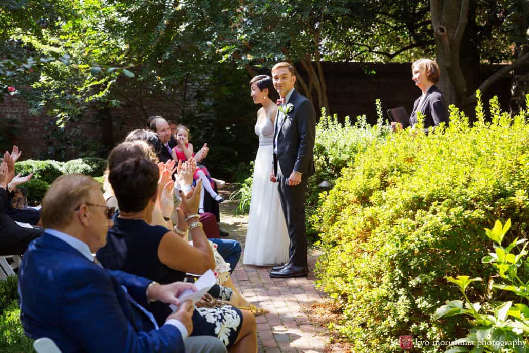 Groom glances at camera as couple exits their ceremony, by candid DC wedding photographer Kyo Morishima