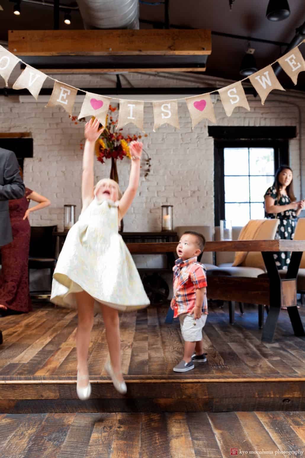 Two young guests jump up to play with flag garland at Virtue Feed and Grain wedding in Old Town Alexandria