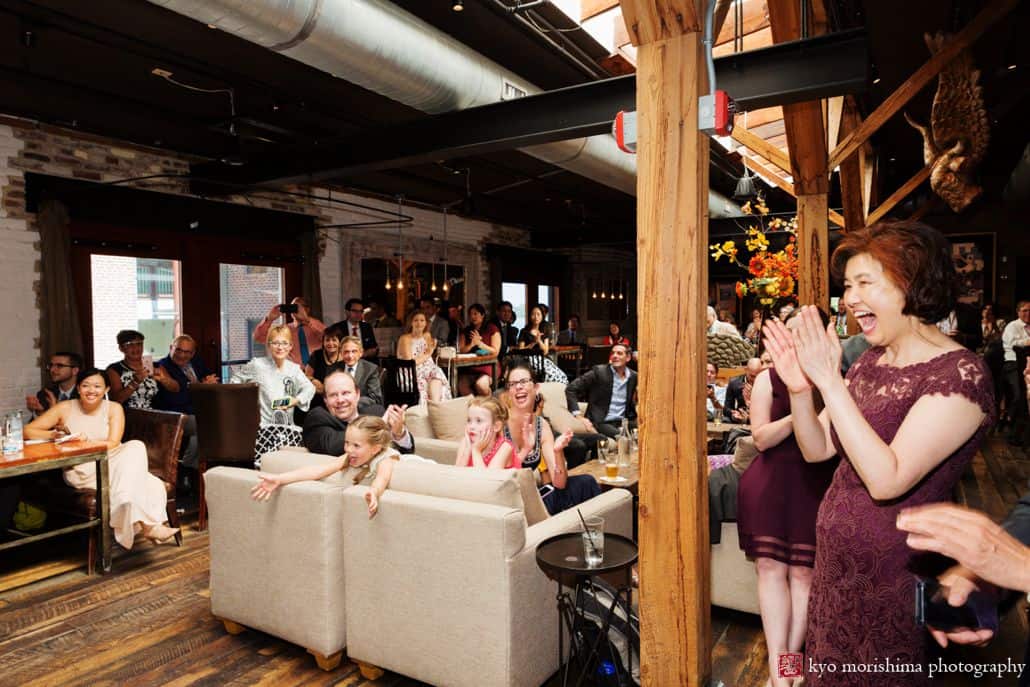 Guests react enthusiastically to first dance at Virtue Feed and Grain wedding; candid moment by DC photographer Kyo morishima