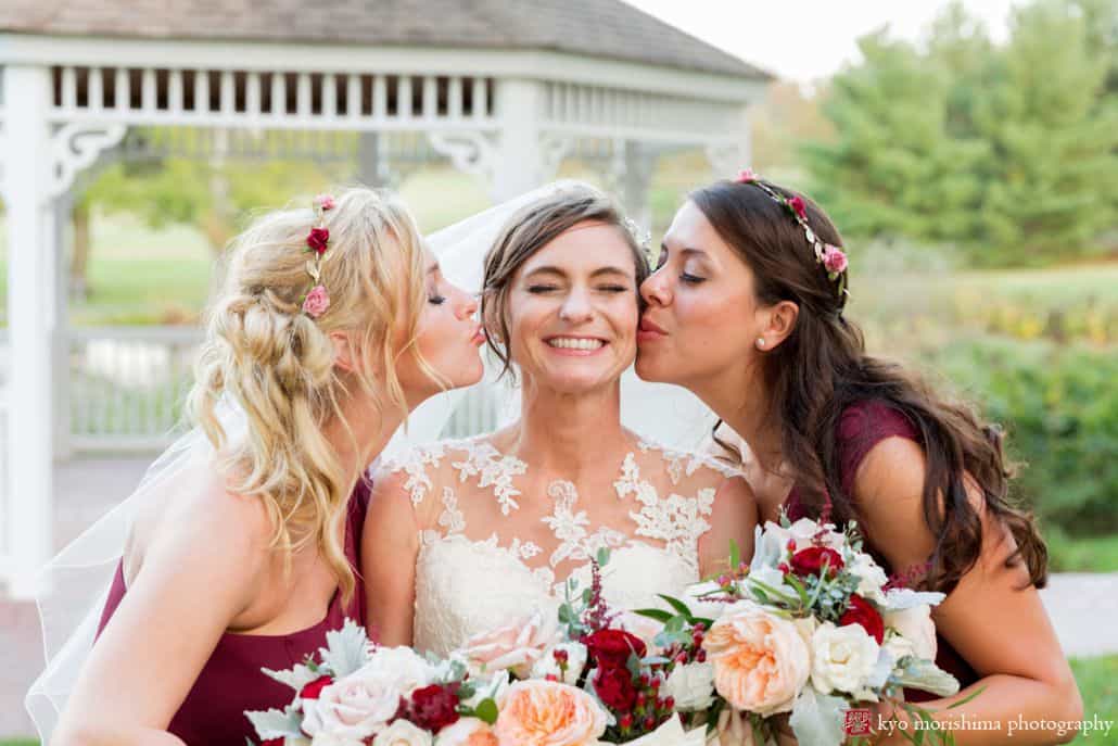 Wedding poses examples: bridesmaids kiss bride in front of gazebo at Chauncey Hotel and Laurie House Garden Pavilion wedding, Princeton, NJ