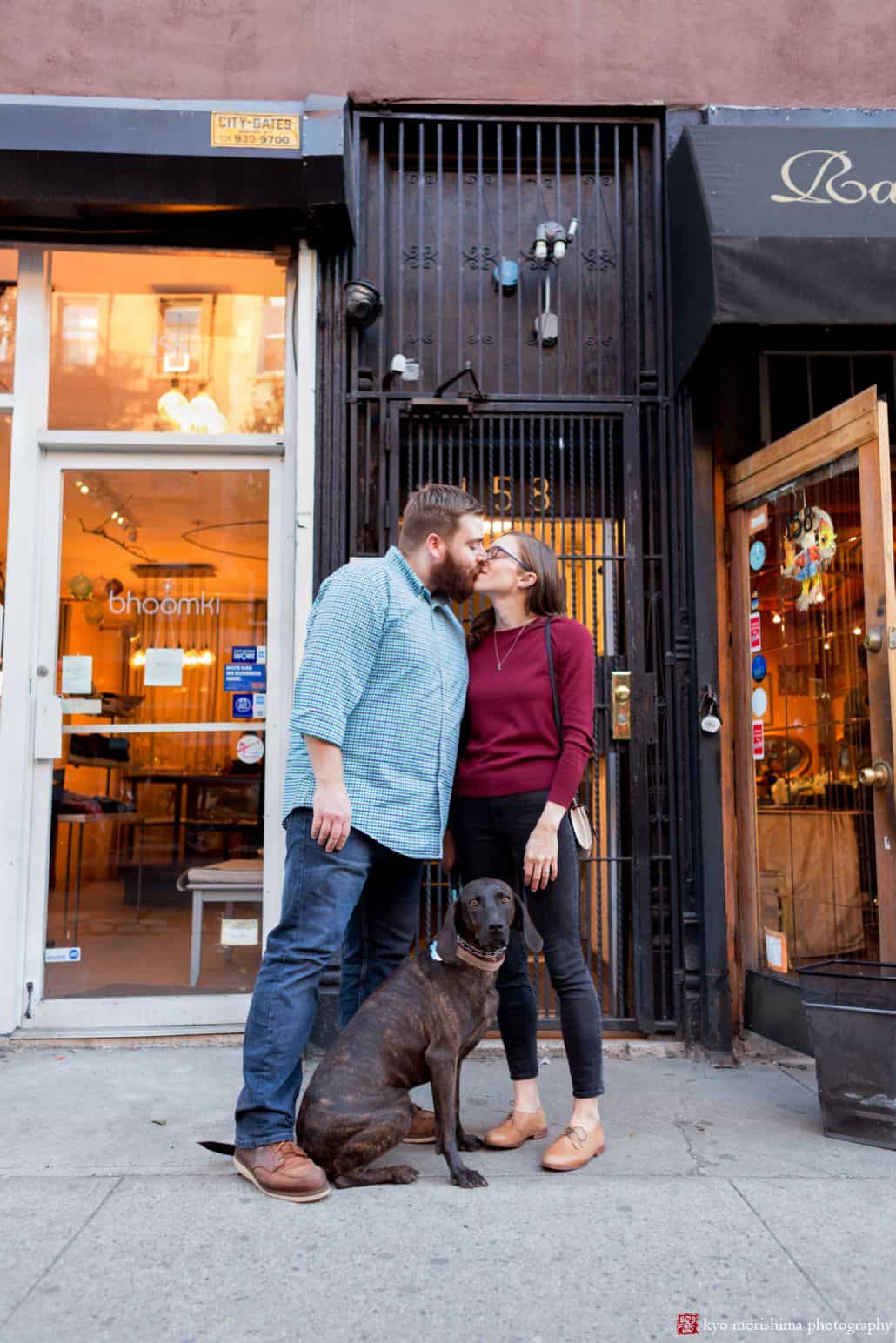 Couple kisses in Brooklyn storefront while holding their Weimaraner dog's leash, by Park Slope photographer Kyo Morishima