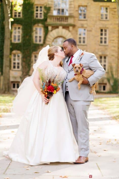 Fall wedding portrait at Princeton University with groom holding small dog; wedding bouquet with fall colors