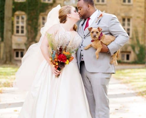 Fall wedding portrait at Princeton University with groom holding small dog; wedding bouquet with fall colors