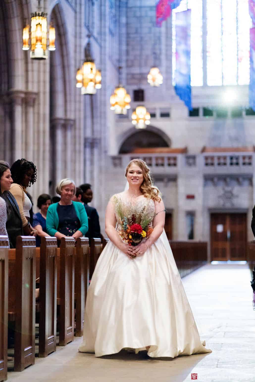 Bride walks down the aisle at Princeton University chapel wearing dress by Christina Wu with fall themed wedding bouquet