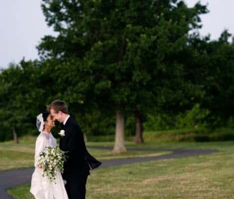 Bride and groom kiss on a path outside Mercer Oaks Country Club with thunderstorm approaching. West Windsor Township, NJ.