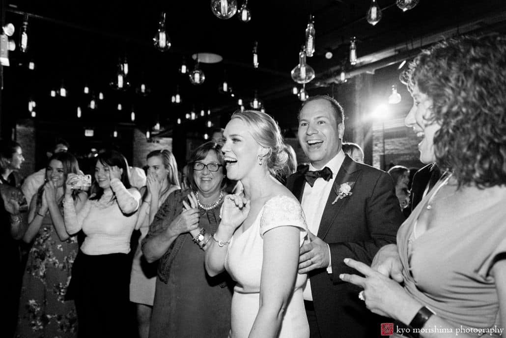 Best documentary wedding photographers NYC: bride and groom react to guests' dancing at Liberty House wedding in Red Hook BrooklynBest documentary wedding photographers NYC: bride and groom react to guests' dancing at Liberty House wedding in Red Hook Brooklyn