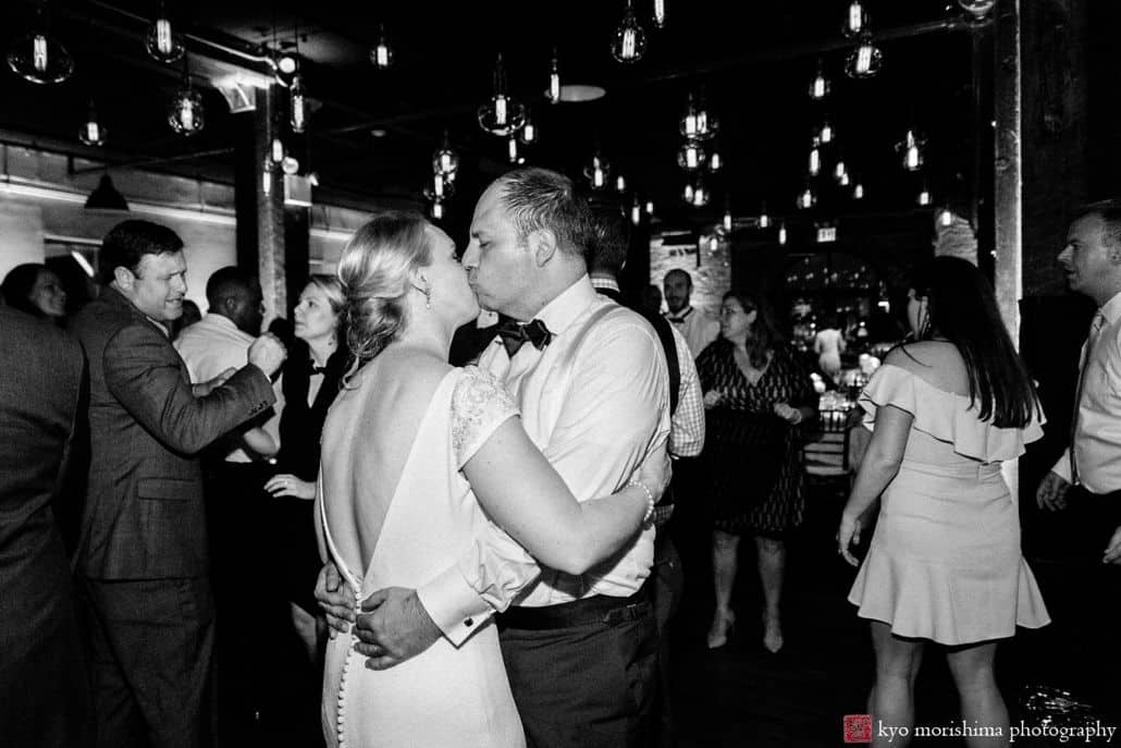Best candid wedding photos: bride and groom kiss on the dance floor, surrounded by their friends, at Liberty House wedding in Red Hook Brooklyn