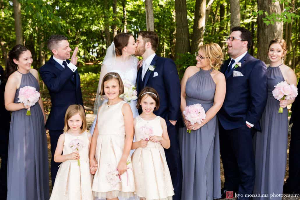 outdoor family posed wedding bridal party photo cute and funny family wedding photo idea bride and groom kiss in front of trees Late Spring Mercer County Boathouse Princeton NJ Wedding