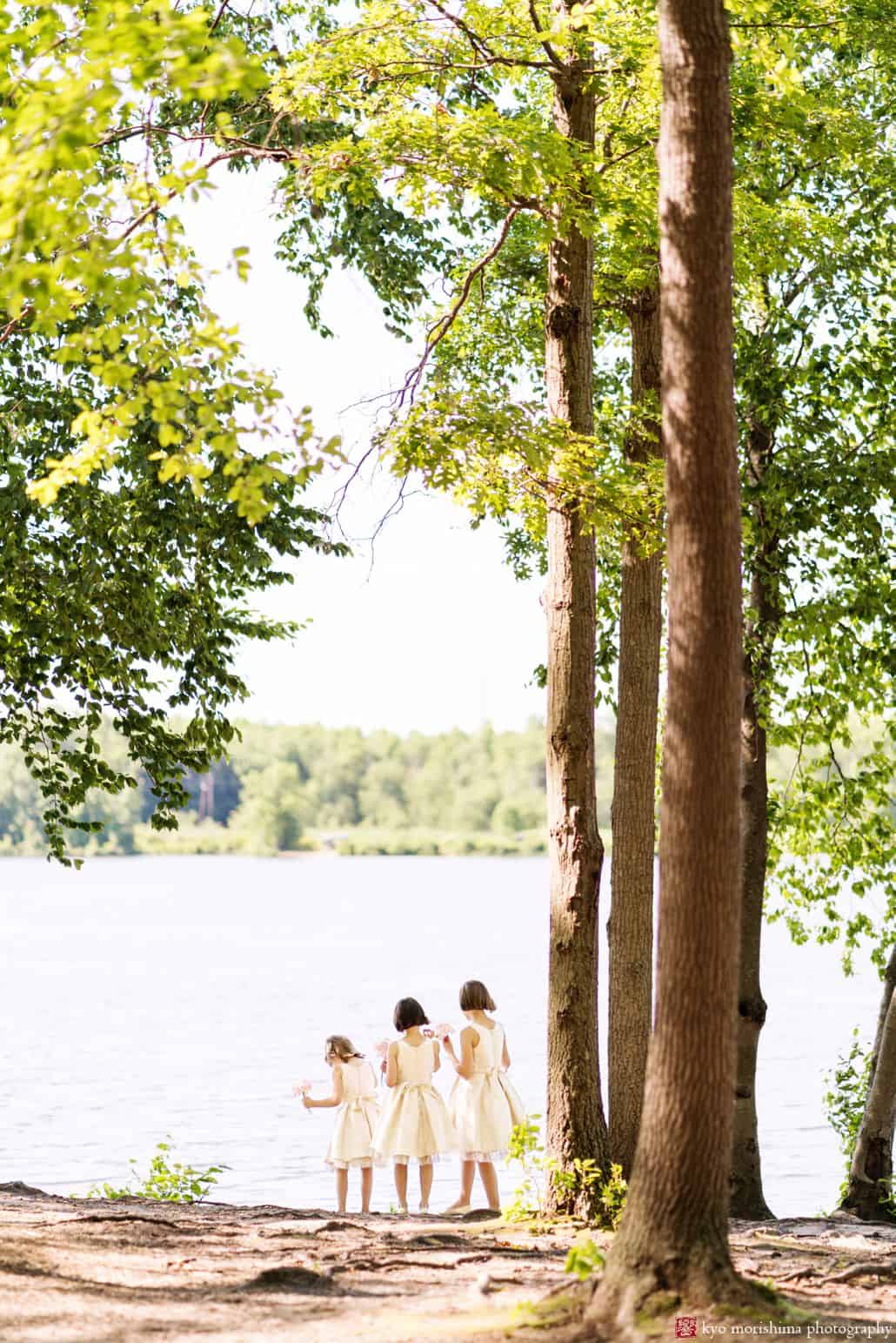 candid flower girls by the water in dresses outdoors standing next to each other looking at the water cute and candid wedding picture idea central NJ photography Late Spring Mercer County Boathouse Princeton NJ Wedding