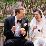 Light-hearted portrait session of a happy groom and bride sitting in a bench, the bride is laughing and holding a cup of ice cream, the groom is smiling holding a glass of ice cream or dessert, photographed by wedding photographer in central NJ Kyo Morishima.