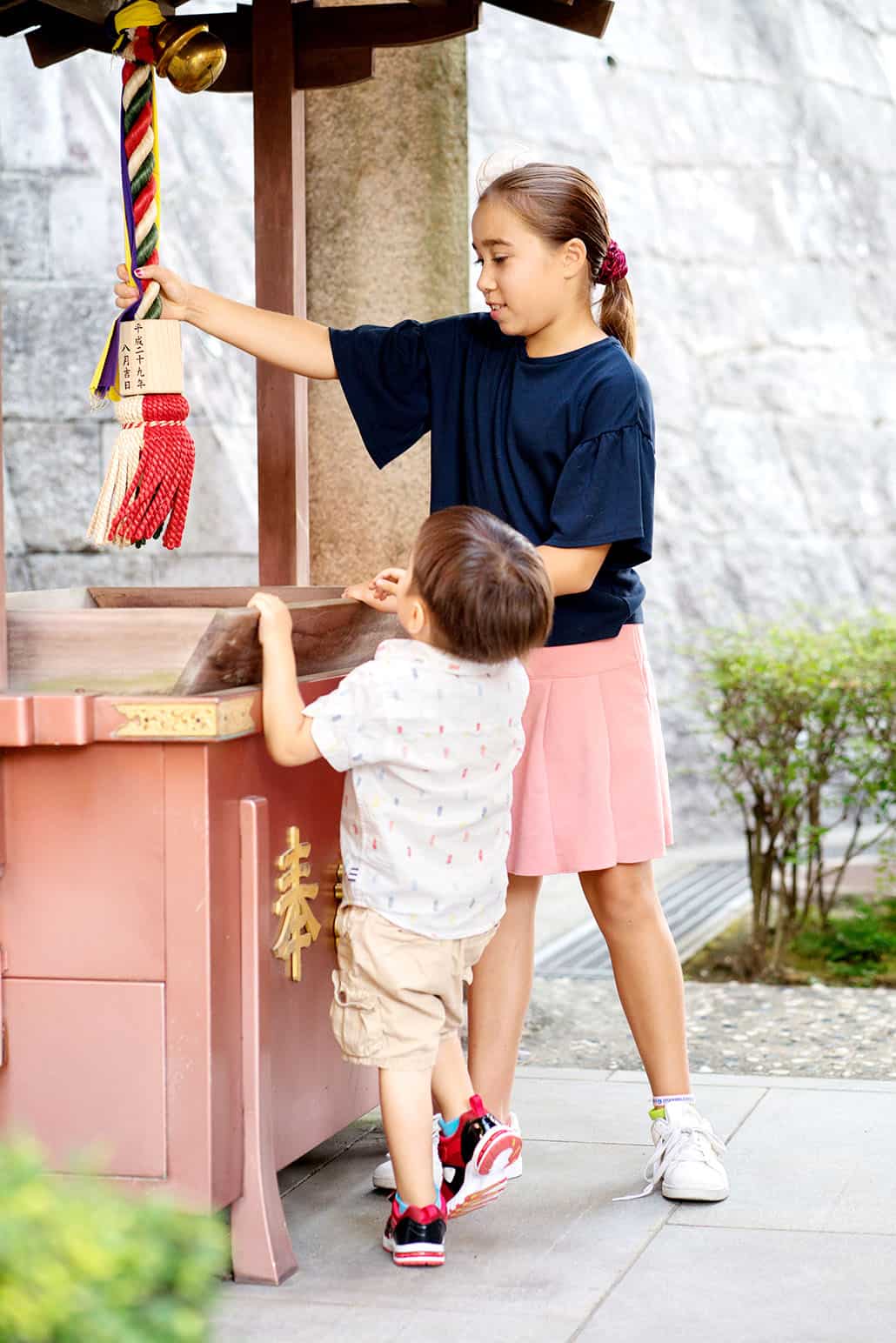 Sister and brother pull the bell rope at a Buddhist temple in Nishinomiya, Japan, photographed by central NJ family photographer Kyo Morishima