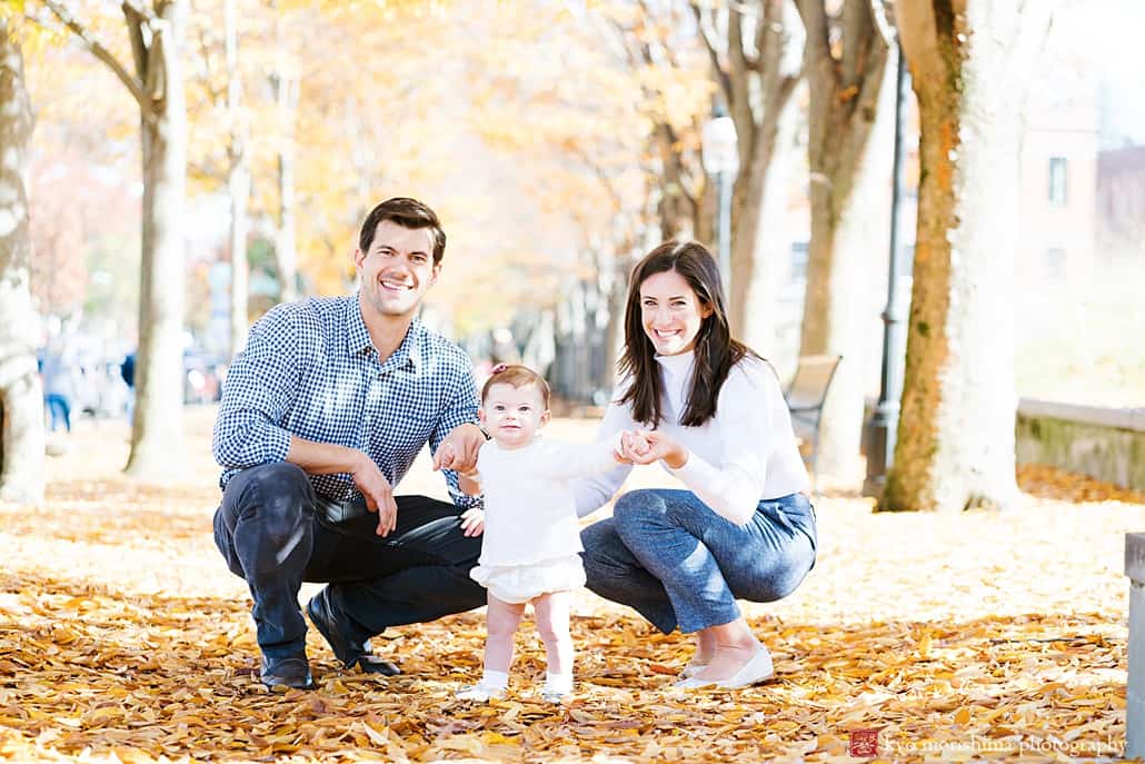 Princeton professional family portrait outdoors with fall foliage in the background, baby holding hands with parents.