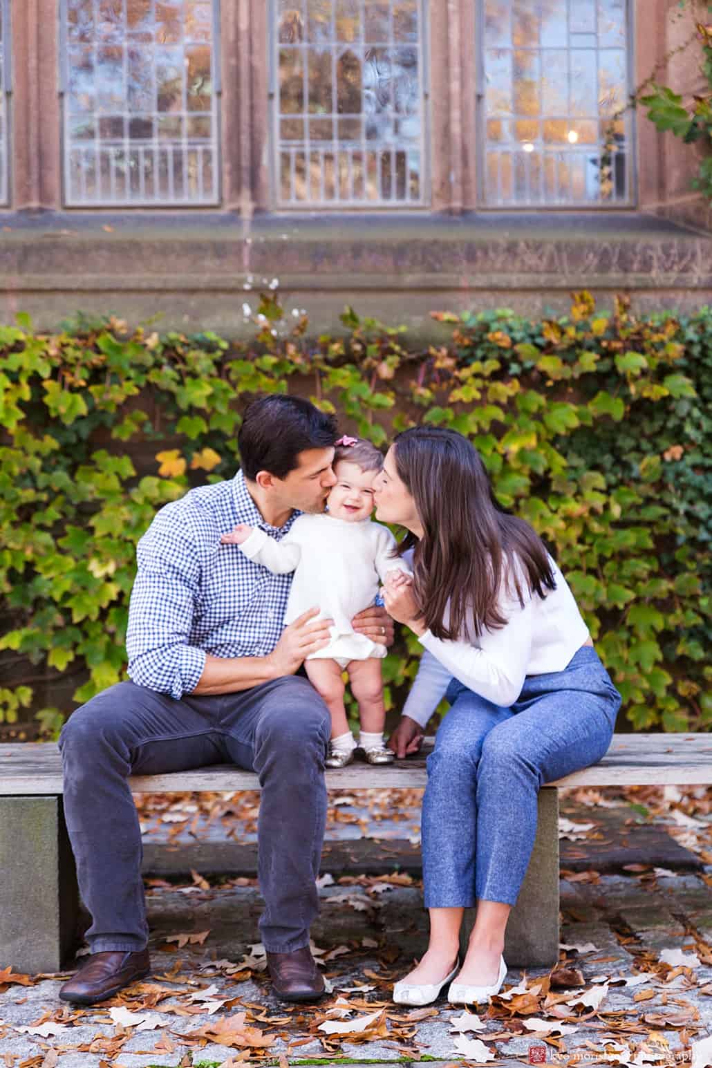 Mom and Dad kiss baby in front of ivy-covered wall on Princeton University campus: central New Jersey family portrait photographer