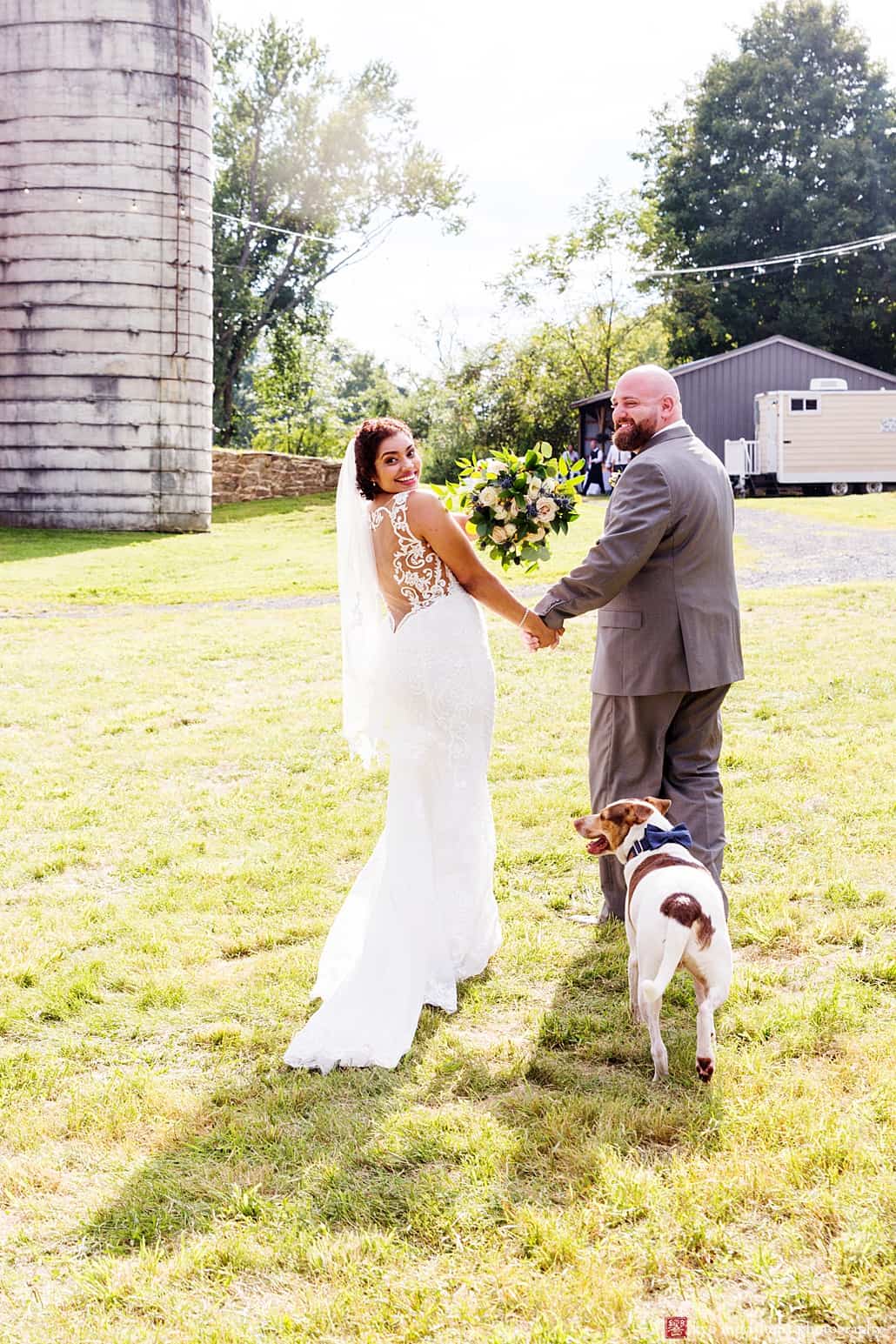 Dog follows bride and groom as they depart outdoor ceremony at Glenmoore Farm, one of the best NJ farm wedding venues in central NJ