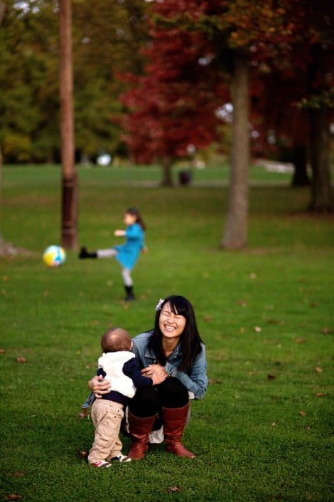 Family playing in the park, kicking a ball and hugging. New Jersey family photography. Relaxed, candid family photos.