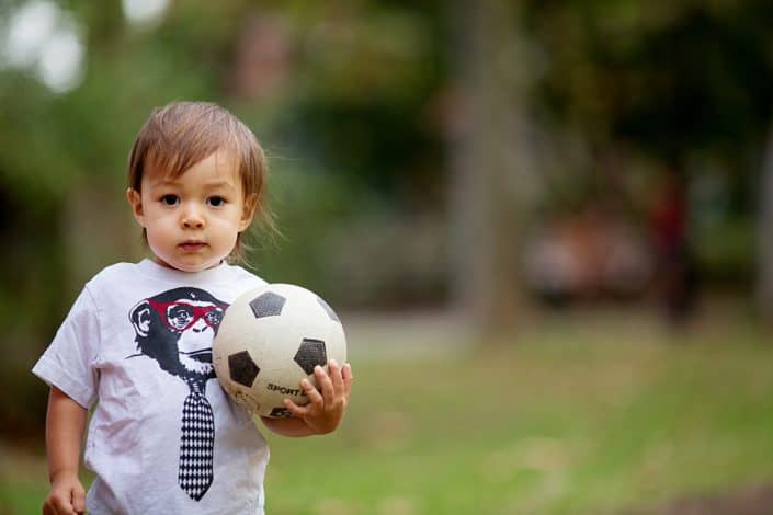 Natural family photos of son playing with soccer ball. NYC child and family photography.