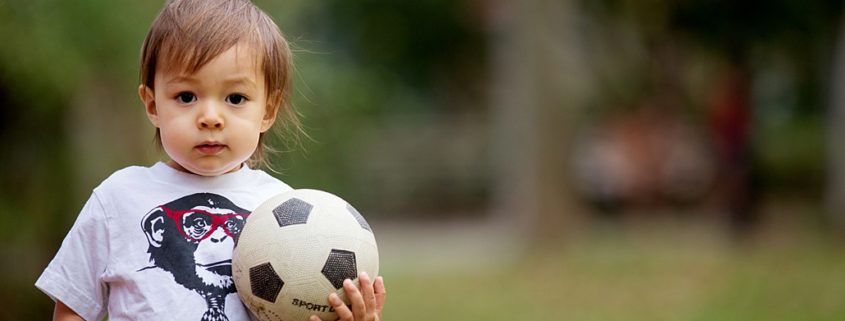 Natural family photos of son playing with soccer ball. NYC child and family photography.