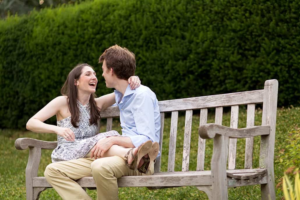 Candid engagement photos: couple laughing on park bench on Princeton University campus