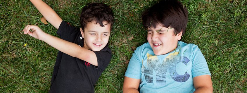 Brothers playing and looking at the clouds in the park. New Jersey family photography. Relaxed, candid family photos.