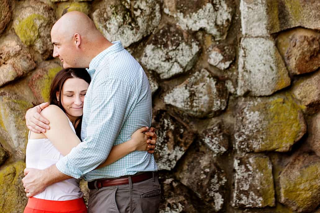 Duke Farms engagement photograph: couple hugs with moss-covered stone wall in background; woman wears lipstick-red skirt family couple kids child children dog pets portrait, NYC, Brooklyn, DE, Philadelphia, Philly, personal branding photography