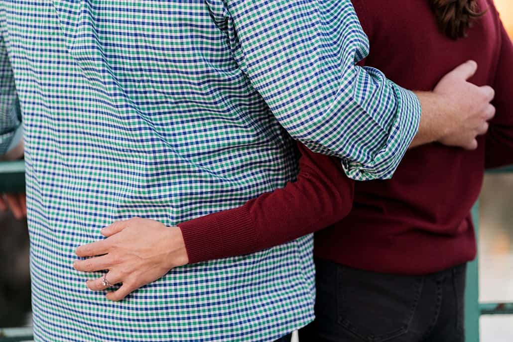 Close-up of couple hugging each other (no faces); man wearing blue checked shirt, woman wearing burgundy sweater. Engagement photo detail shot in Brooklyn, NY. family portrait