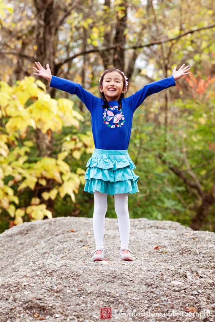 Daughter playing outside, hands up, climbing a rock. Silly, fun child Delaware & Raritan Canal State Park Trail Kingston portraits. New Jersey family photography
