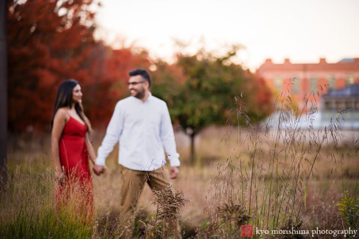 Princeton University Campus Firestone Library NJ candid documentary engagement portrait session fall autumn a couple red dress European brick building wooded door street dusk sunset hold hands smile looking at each other walking