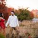 Princeton University Campus Firestone Library NJ candid documentary engagement portrait session fall autumn a couple red dress European brick building wooded door street dusk sunset hold hands smile looking at each other walking