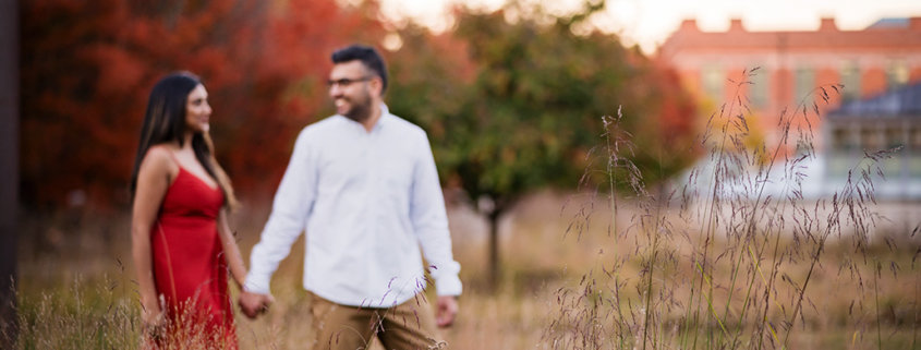 Princeton University Campus Firestone Library NJ candid documentary engagement portrait session fall autumn a couple red dress European brick building wooded door street dusk sunset hold hands smile looking at each other walking