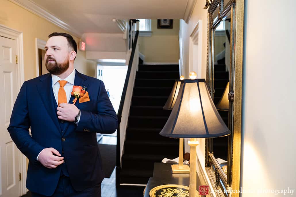 at Fall The Inn at Fernbrook Farm Chesterfield NJ Wedding groom in his suit looking at himself reflection big mirror while getting ready in a suite room