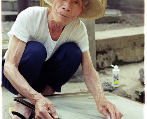 Old man washing his window screen with hot spring water in Yufuin Oita Japan