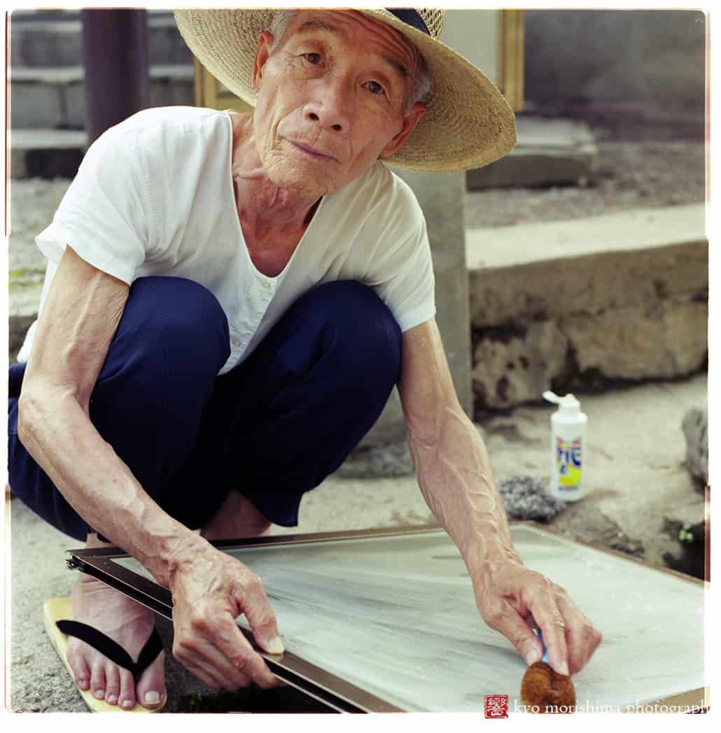 Old man washing his window screen with hot spring water in Yufuin Oita Japan
