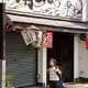 A boy smiling walking by a Takoyaki restaurant, Japan
