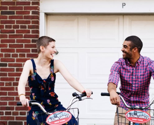 Governor's Island couple editorial street portrait engagement NYC lovers cycling dating smiling laughing looking at each other