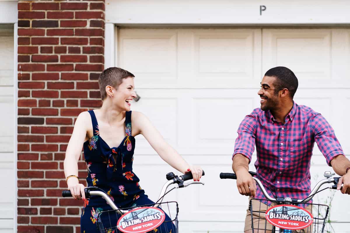 Governor's Island couple editorial street portrait engagement NYC lovers cycling dating smiling laughing looking at each other